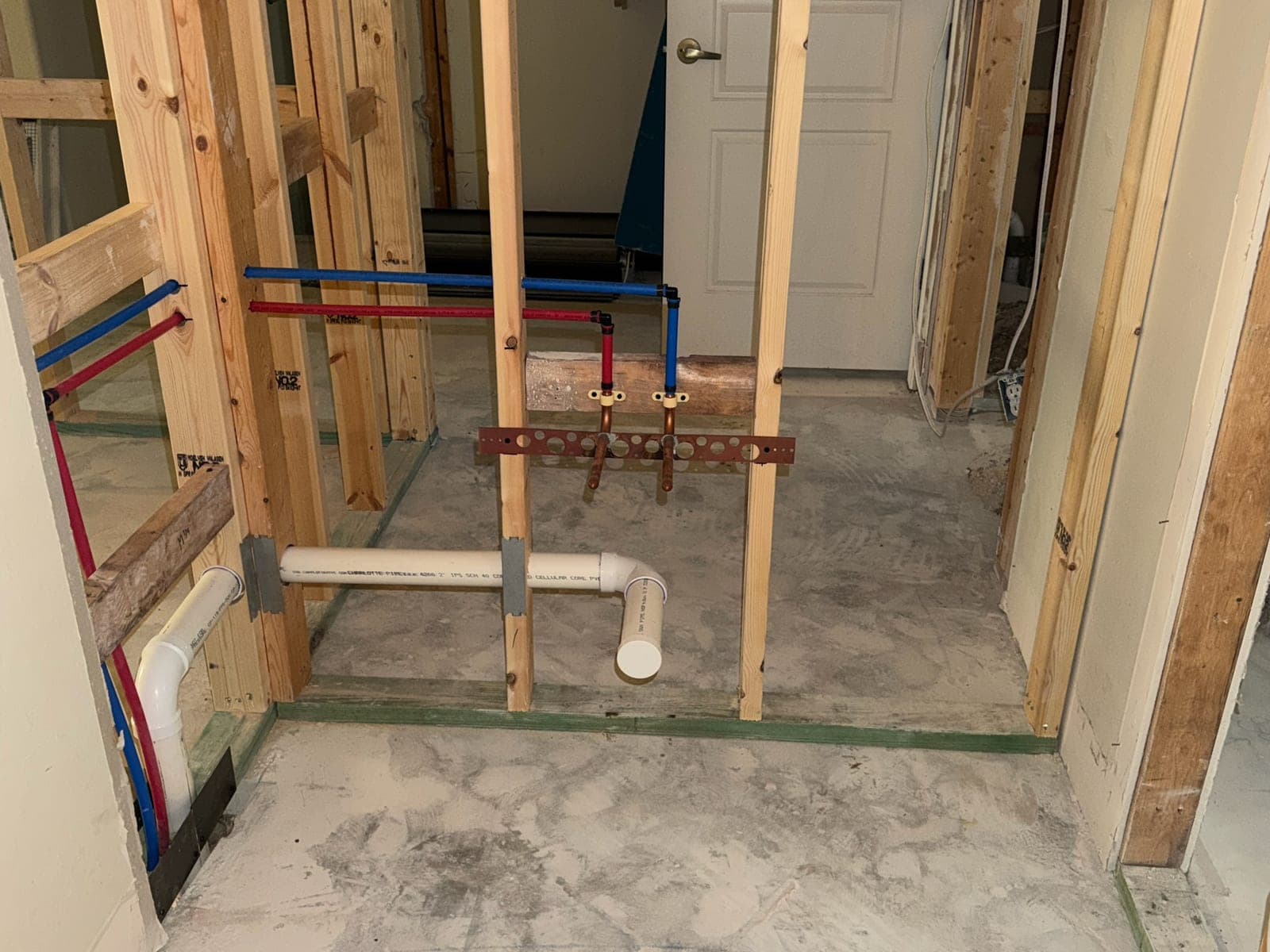 Bathroom rough-in with PEX supply stub-outs and PVC waste lines between wall studs