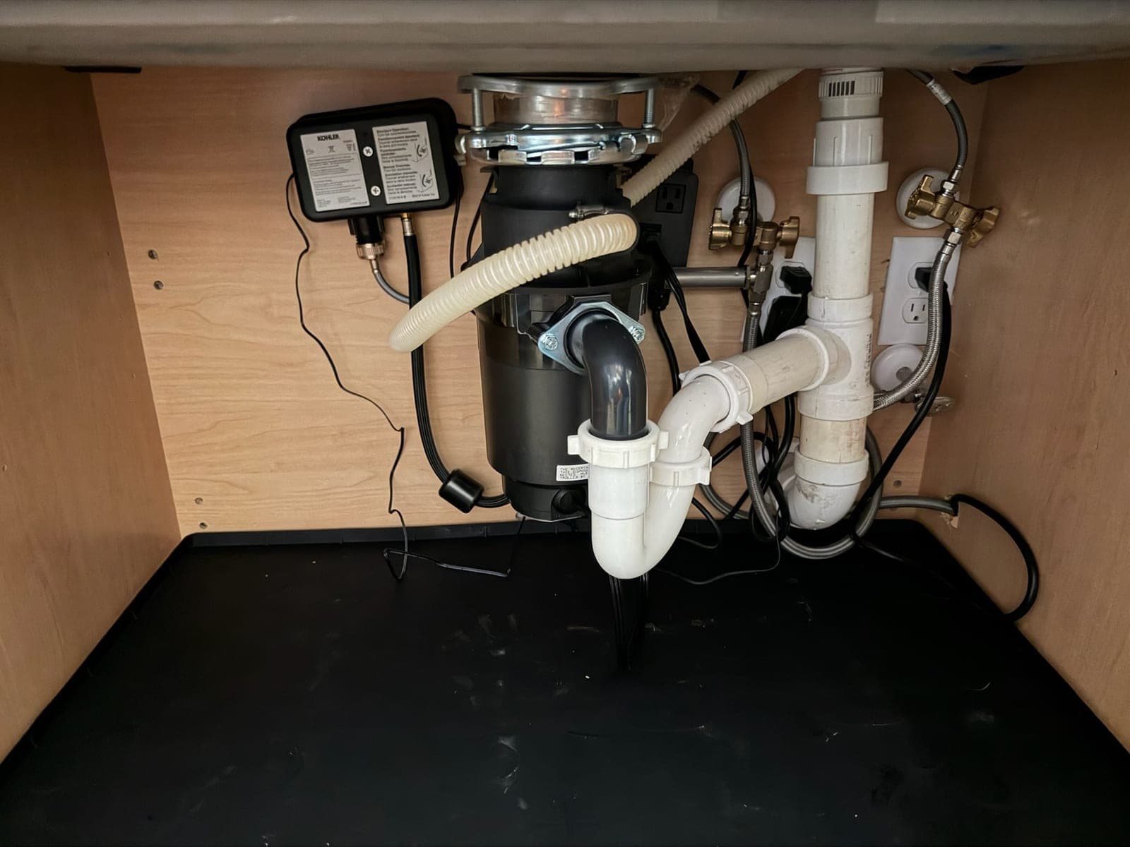 Under-sink cabinet with a new garbage disposal, P-trap, braided supply lines and quarter-turn stops
