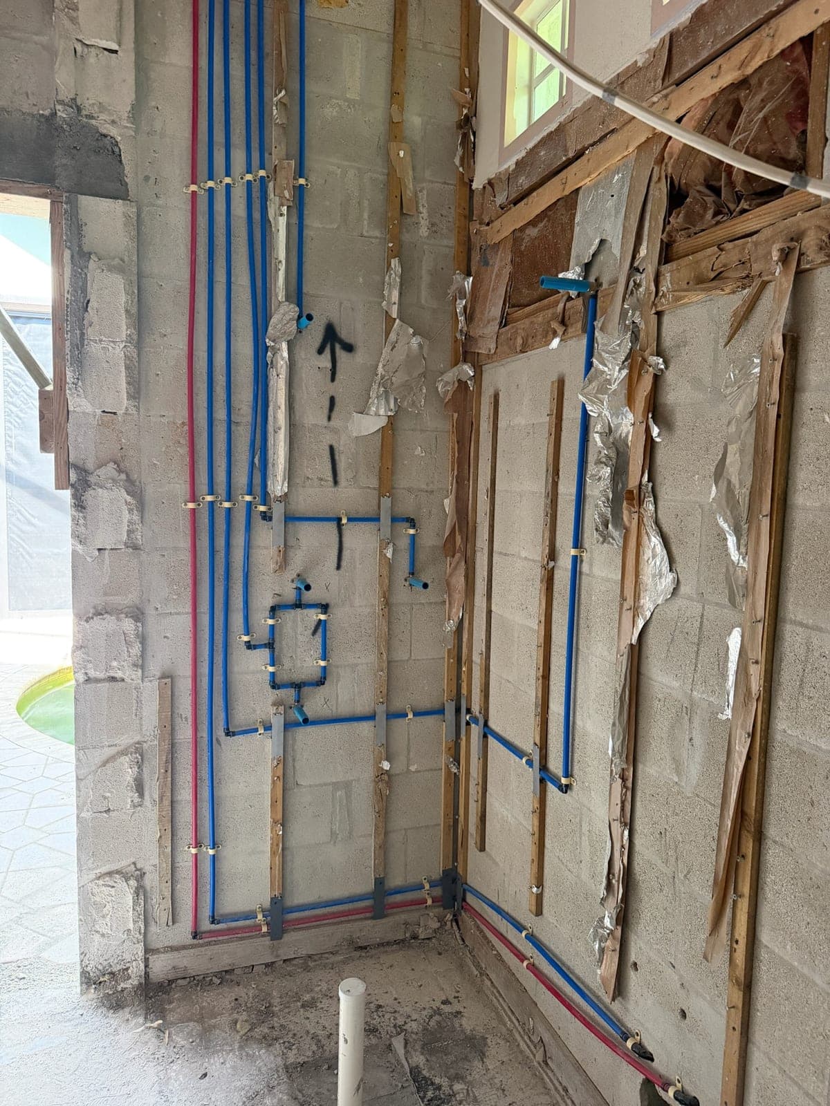 Blue and red PEX supply lines run and strapped across a block wall during a whole-home repipe
