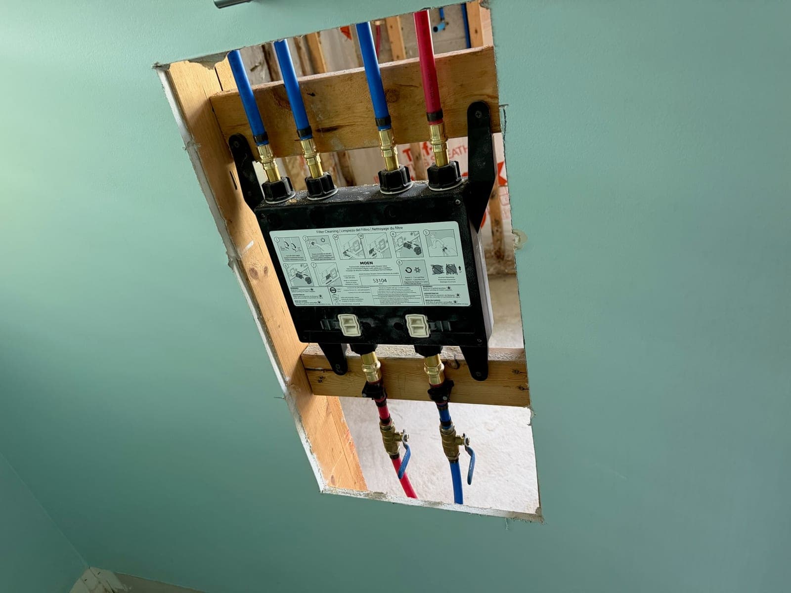 Moen digital shower valve mounted in a wall opening with PEX hot and cold supply lines and shutoffs connected