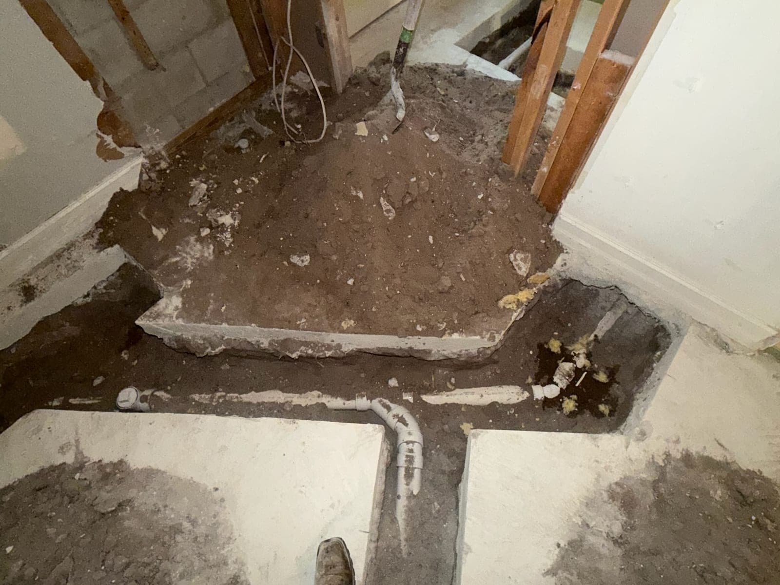 Concrete slab opened up with a new PVC drain line and cleanout fitting in place