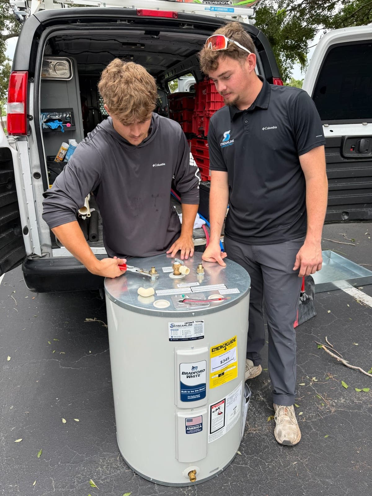 Two Streamline technicians prepping a Bradford White water heater at the back of the service van