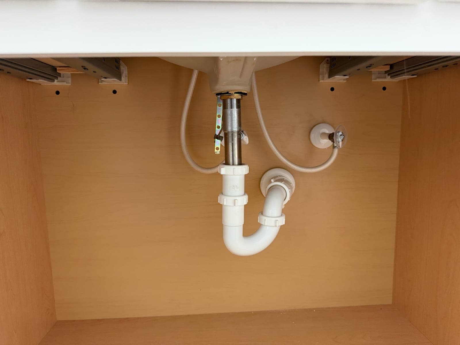 Clean white P-trap and braided supply lines under a bathroom vanity