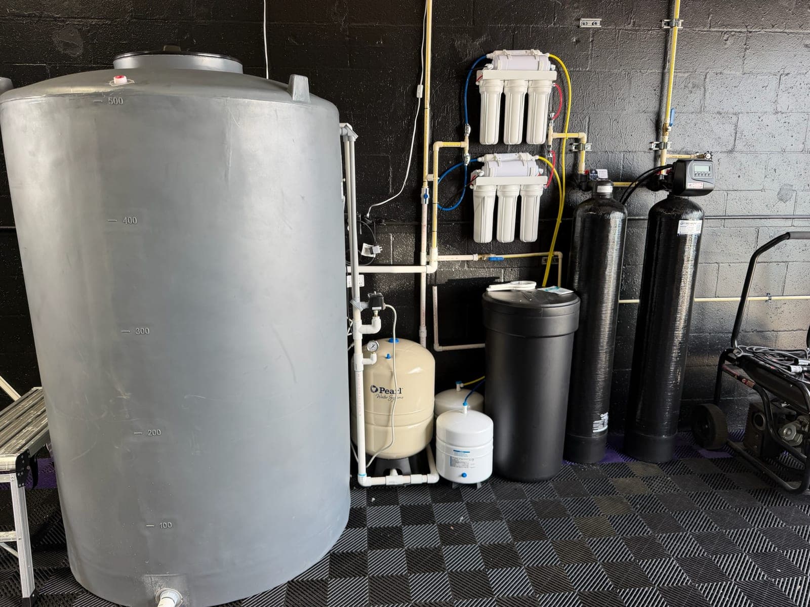 Whole-home water treatment installation with softener and carbon tanks, multi-stage filters, pressure tank and storage tank